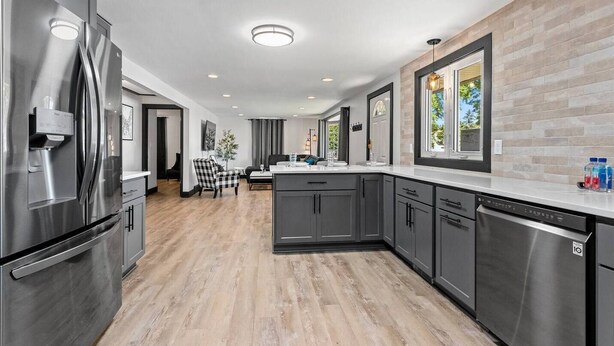 A modern kitchen with stainless steel appliances, grey cabinetry, and a wooden floor. - 5BR House by Lambeau with Game Garage (Green Bay)