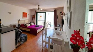 A compact living space with a bed, kitchenette, dining area, and a balcony with a view. - Mareverde Sun apartment, pool view (Costa Adeje)