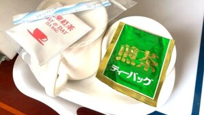 A white tray with a white cloth, a green packet, and a plastic bag with text. - Hotel Robinson INN Ryukyu Tabikan MW1 (Okinawa)