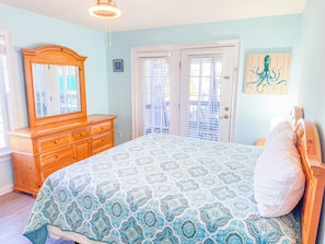 A bedroom with a bed, dresser, and a painting on the wall. - Casa de Verde (North Myrtle Beach)