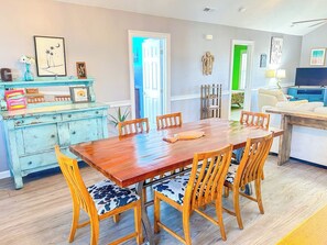A dining area with a wooden table and chairs, a blue dresser, and a green door.