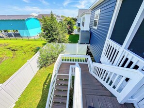 A residential deck with white railings, a green lawn, and a house with blue siding.
