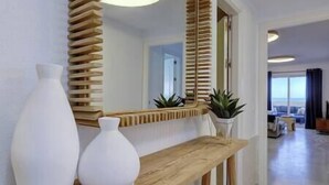 A modern interior with a wooden console table, two white vases, and a mirror with wooden slats. - Front Row Penthouse Apartment on Carvajal Beach (Fuengirola)