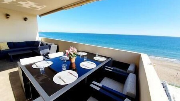 A dining area with a table set for four, overlooking the ocean. - Front Row Penthouse Apartment on Carvajal Beach (Fuengirola)