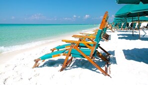 A beach with rows of wooden beach chairs and umbrellas.
