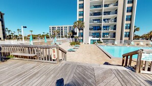 A pool area with a wooden deck, lounge chairs, and a sign indicating pool entry. - Okaloosa Island, Beach Service Included, Emerald Isle 206 (Fort Walton Beach)