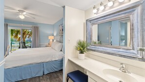 A bedroom with a bed, a nightstand, a lamp, and a potted plant. - Okaloosa Island, Beach Service Included, Emerald Isle 206 (Fort Walton Beach)