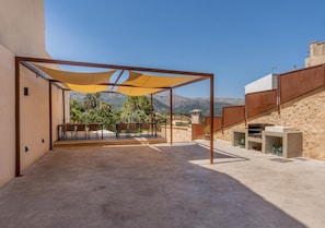 An outdoor patio area with a covered seating area, a barbecue grill, and a view of the surrounding landscape.