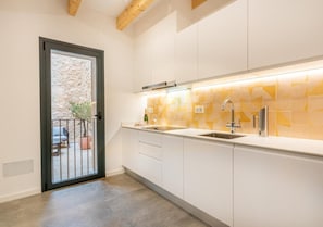 A modern kitchen with white cabinets, a stainless steel sink, and a backsplash with geometric yellow tiles.