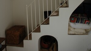 A staircase with a white railing leading to a landing. A wicker basket is placed on the landing, and a small, dark object is on the floor near the bottom of the stairs. - old farmhouse on the sea (Gaeta)