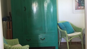 A room with a large teal wardrobe, two wicker chairs with blue cushions, and a wall-mounted hat collection. - old farmhouse on the sea (Gaeta)