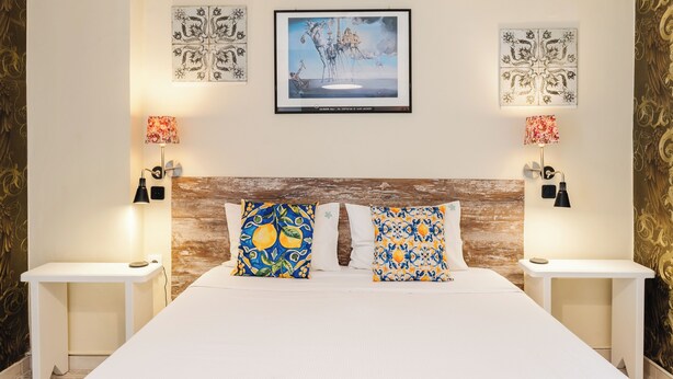 A hotel room with a large bed, two bedside tables, a wooden headboard, and decorative wall art. - Palaiopolis Maison by Konnect, Mon Repos (Corfu)