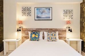 Une chambre d’hôtel avec un grand lit, deux tables de chevet, une tête de lit en bois et des œuvres d’art décoratives au mur.