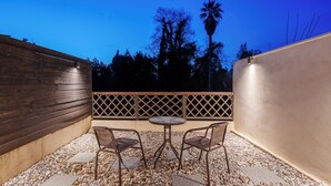 An outdoor patio with a table and chairs, a wooden wall, and a palm tree in the background. - Palaiopolis Maison by Konnect, Mon Repos (Corfu)