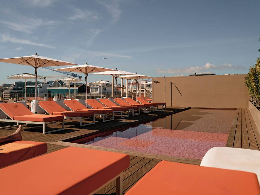 Ein Poolbereich auf dem Dach mit Liegestühlen und Sonnenschirmen, einer Holzterrasse und blauem Himmel.