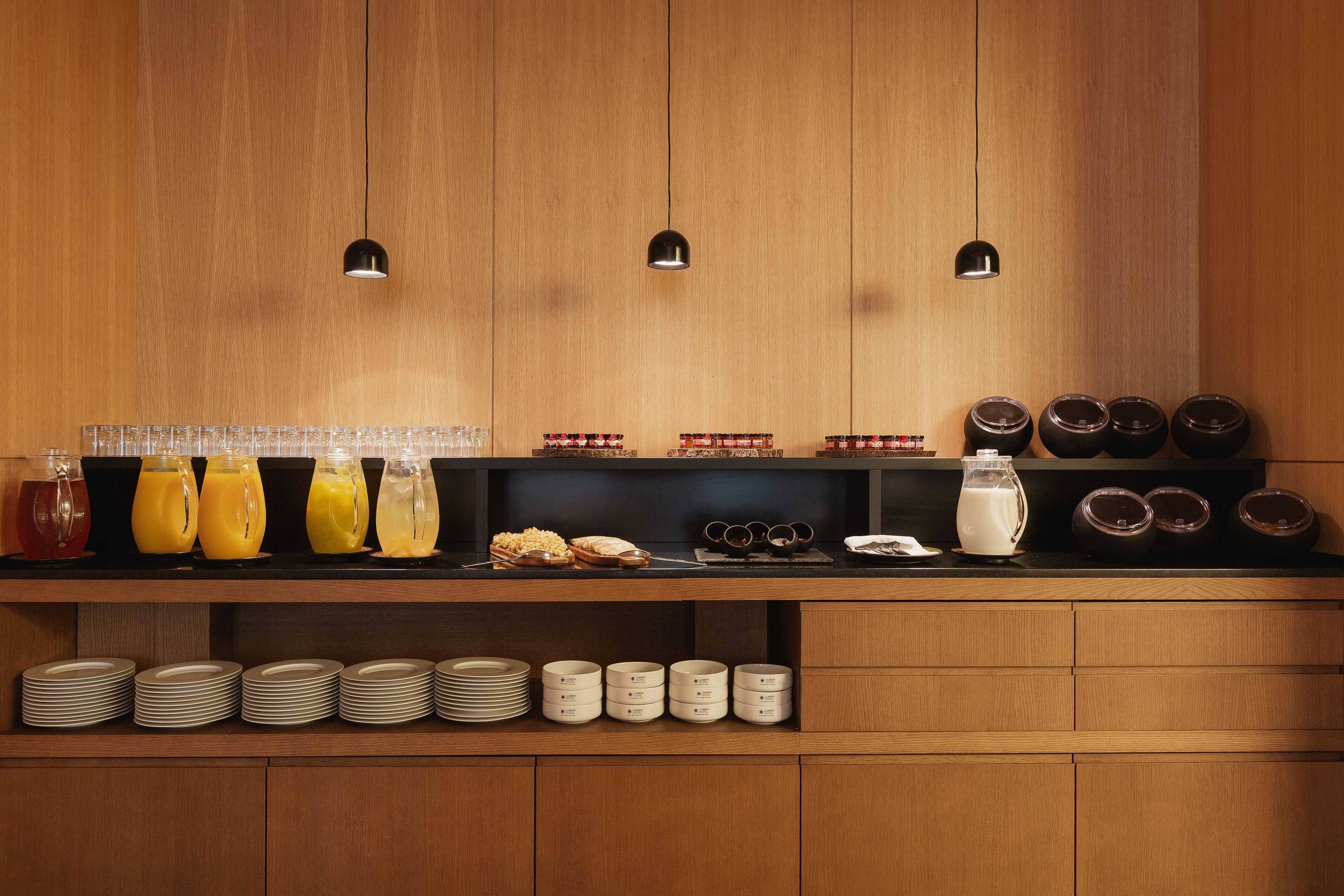 A breakfast buffet with various food and drink options, including juices, cereals, and milk.