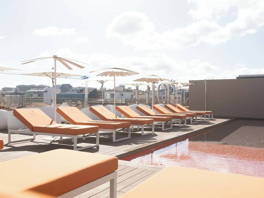 A rooftop pool area with sun loungers and umbrellas.