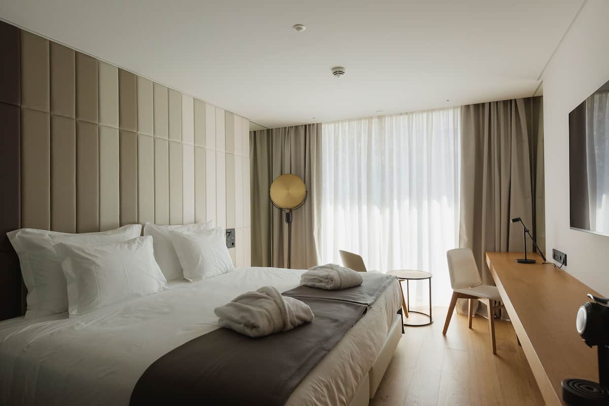 A modern hotel room with a large bed, a desk, and a chair.
