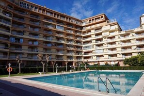 A multi-story hotel with balconies, a swimming pool, and a clear sky. - Jardin (Gandia)