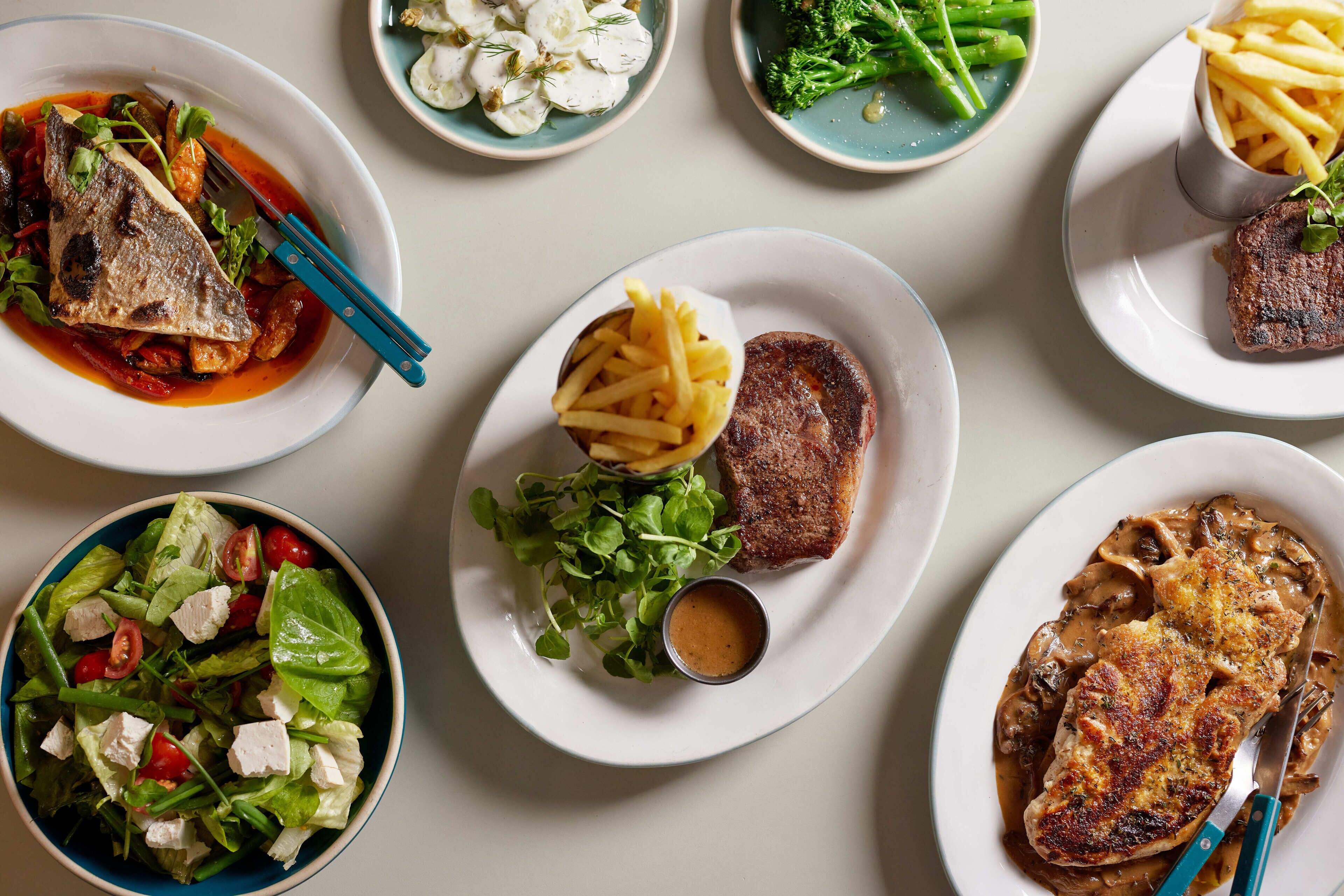 Variedad de platos que incluyen pescado, carne y ensaladas, lo que sugiere una amplia selección de comidas.