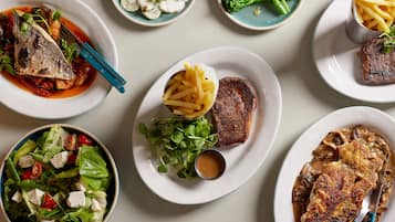 Variedad de platos que incluyen pescado, carne y ensaladas, lo que sugiere una amplia selección de comidas.