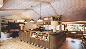 Angolo bar in legno con un bancone che espone diversi oggetti, luci a sospensione e vista sull'esterno.