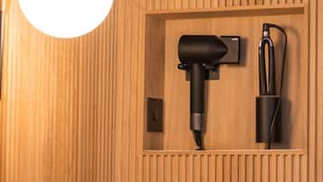 Ein an der Wand befestigter Haartrockner und eine Ladestation in einem raumausgestatteten Holzzimmer.