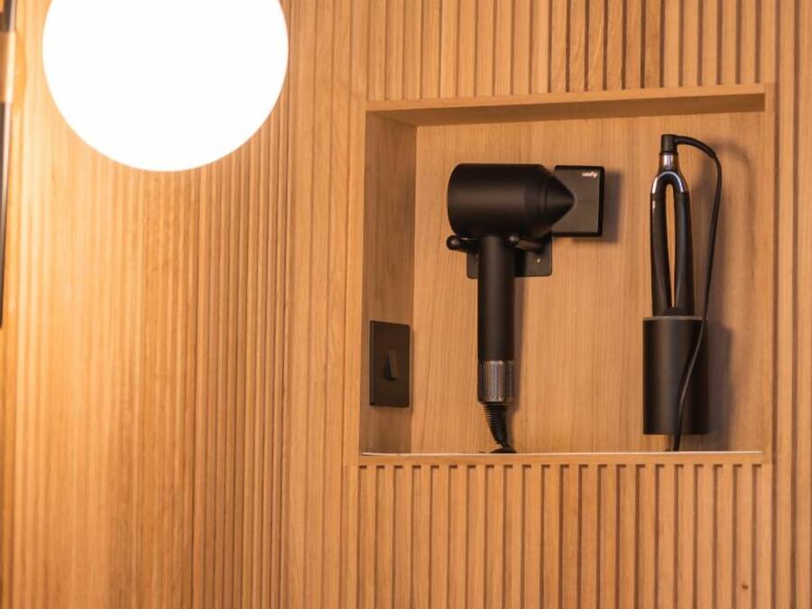 A wall-mounted hairdryer and a charging station in a wooden panelled room.