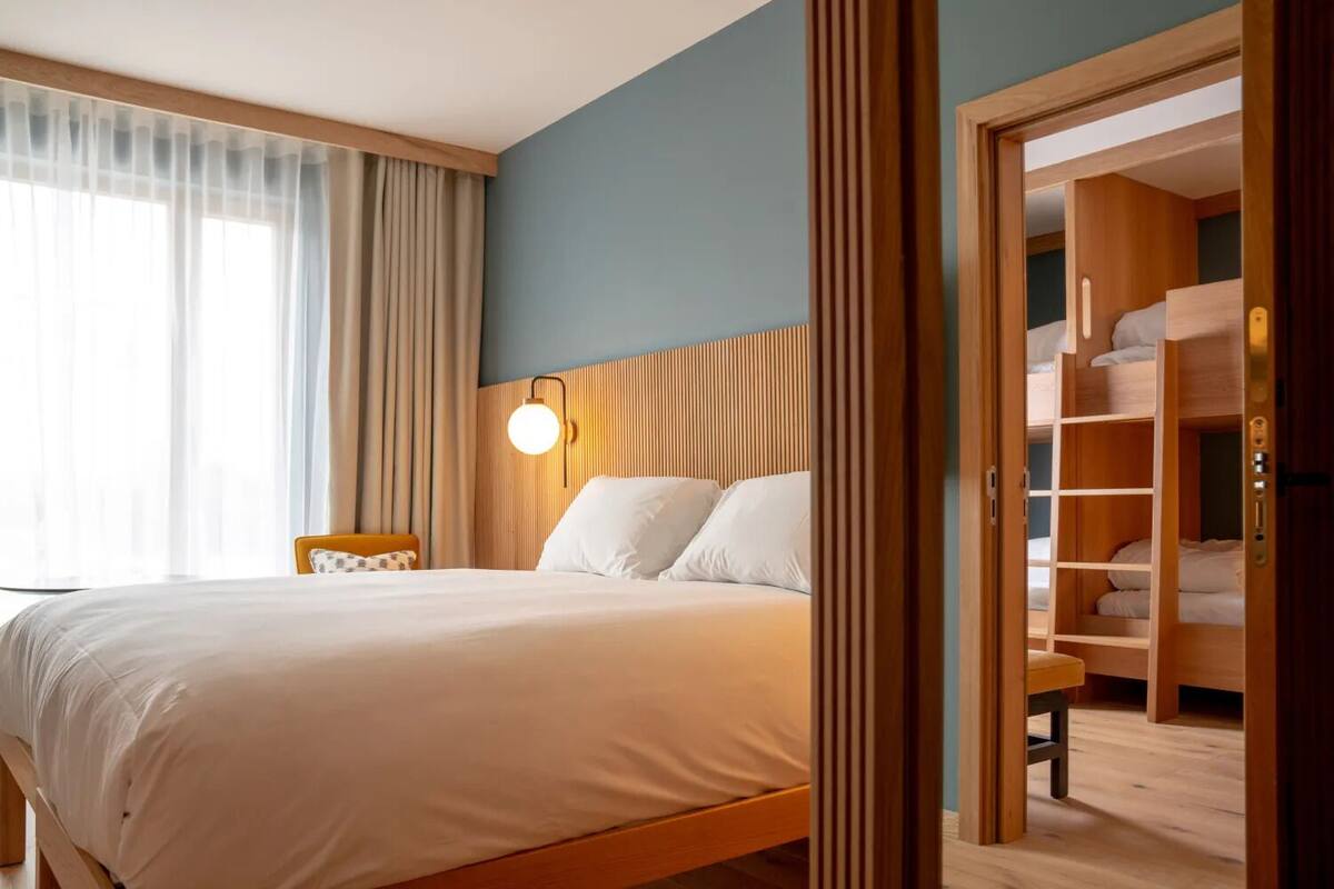 A hotel room with a bed, a bedside table, a lamp, and a wooden wardrobe.