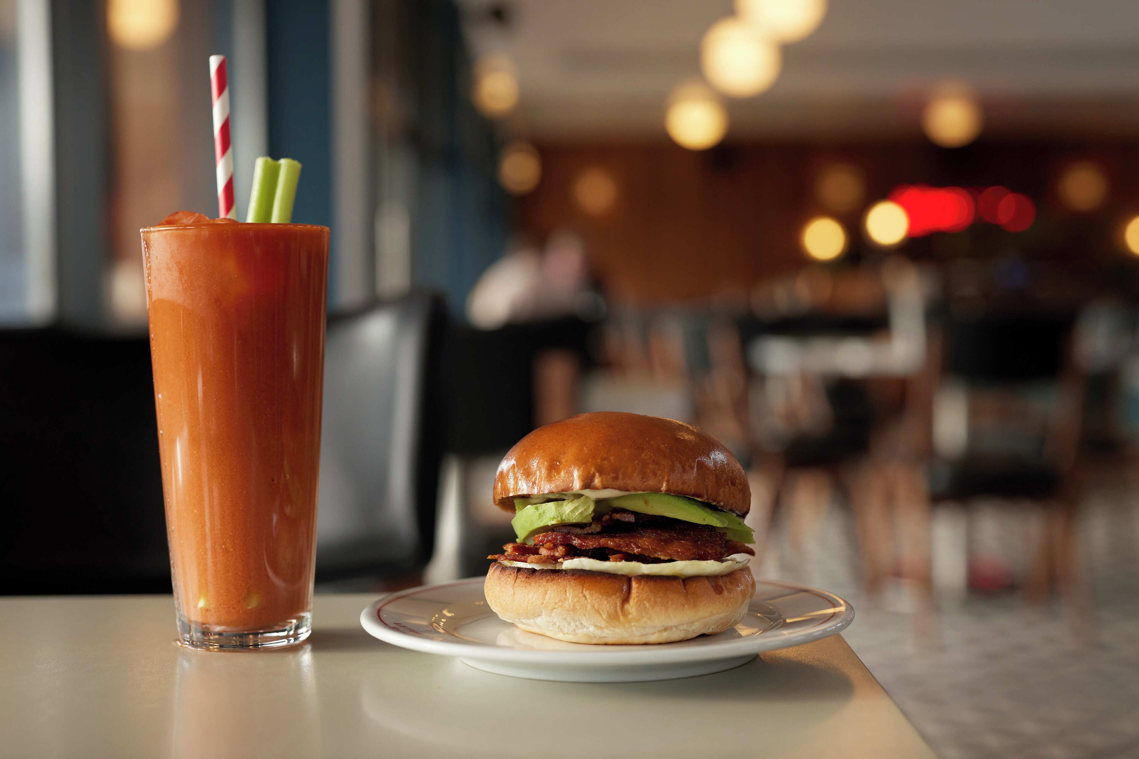 Een hamburger en een glas rood drinken op een tafel in een restaurant.