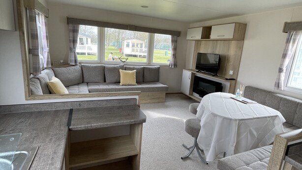 Ein kompaktes Wohnmobil-Interieur mit Küchenzeile, Sitzgruppe und Fernseher.