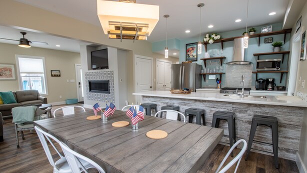 Une cuisine moderne dotée d’un îlot central, de chaises blanches et d’une table à manger décorée de drapeaux américains.