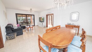 Un amplio espacio de estar con una mesa de comedor de madera, asientos cómodos y un gran ventanal que ofrece vistas al exterior.