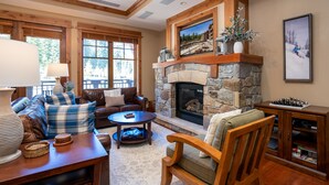 Una sala acogedora con chimenea de piedra, muebles de cuero y un amplio ventanal.