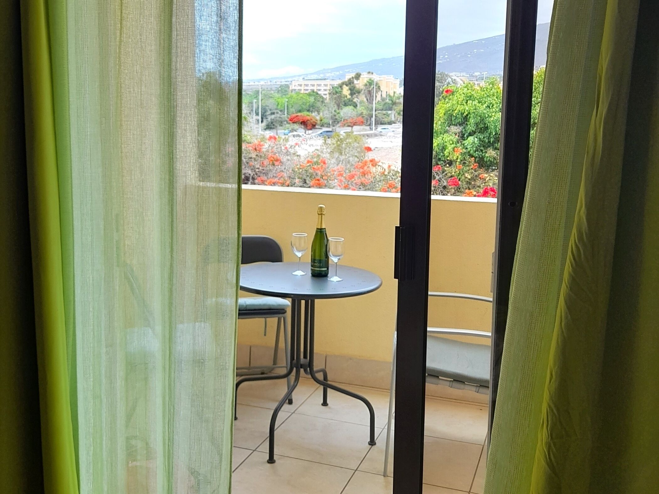 A balcony with a table, a chair, and a bottle of champagne.