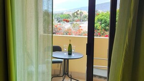 Un balcone con tavolo, una sedia e una bottiglia di champagne.