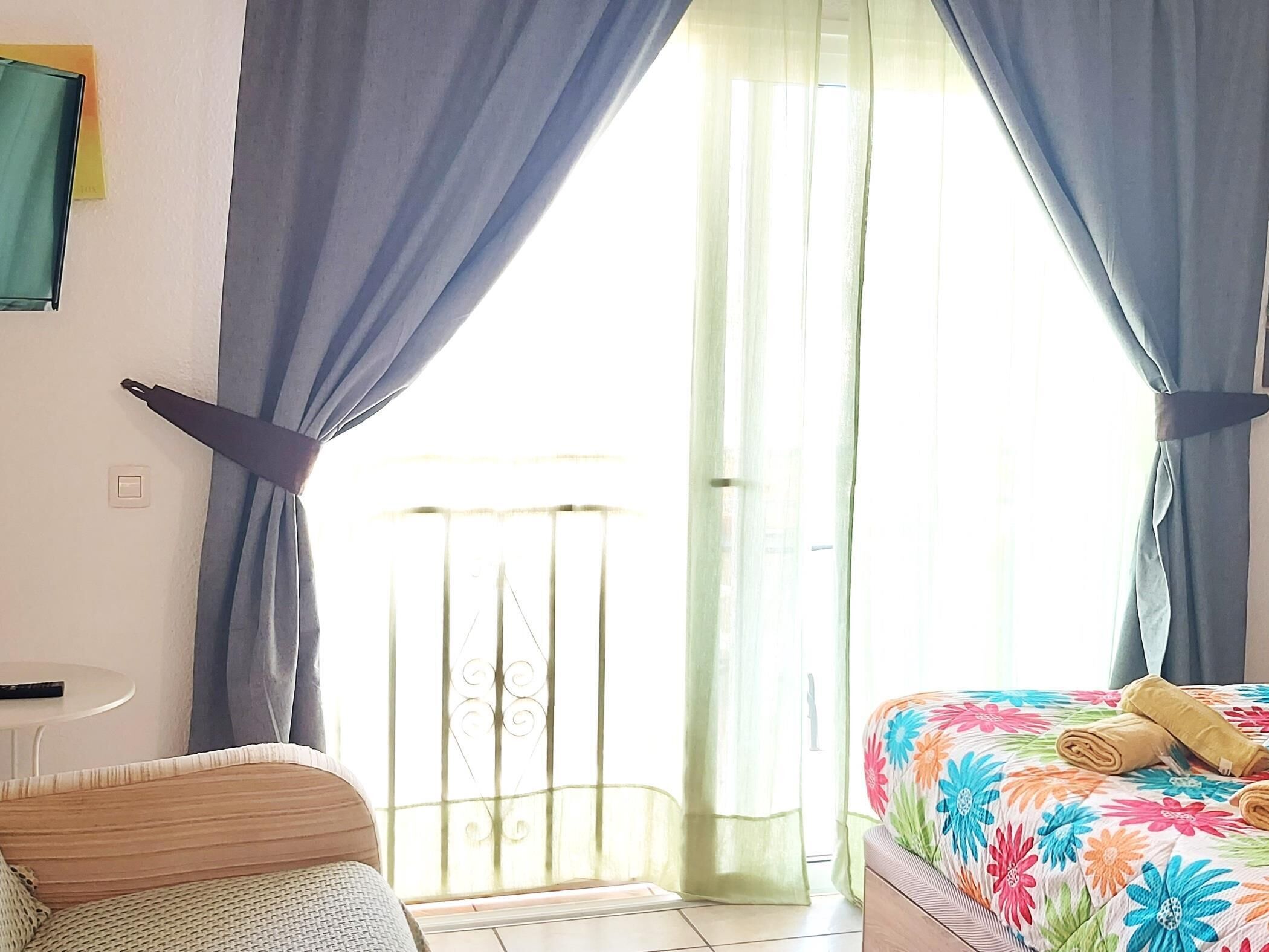 A bedroom with a bed, a chair, and a window with curtains.