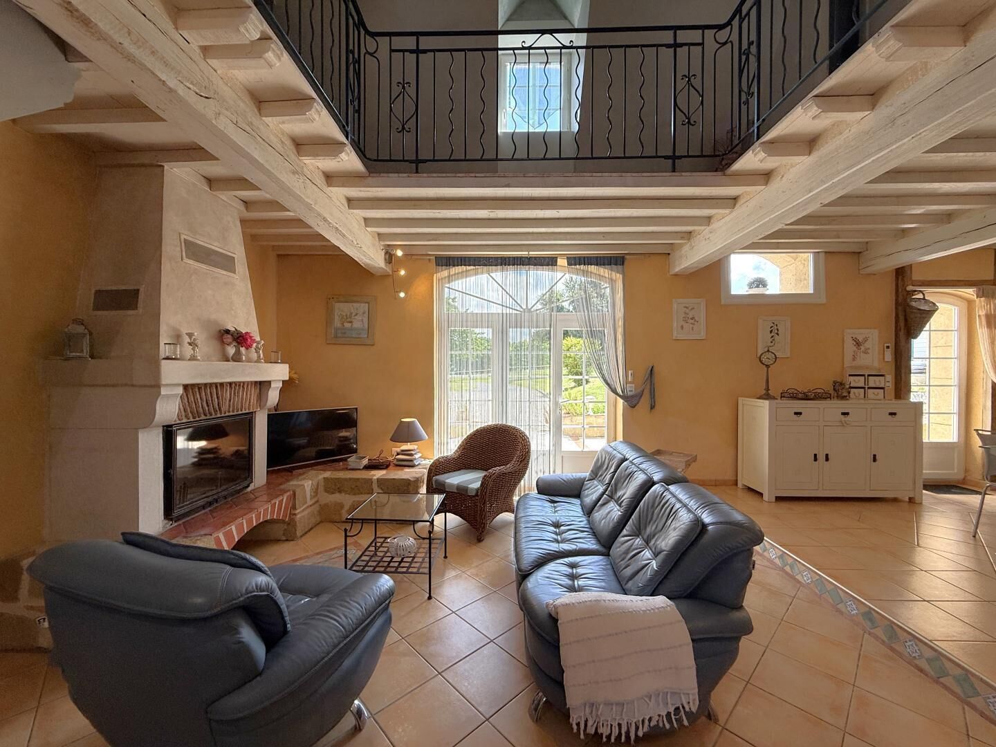 Ein Wohnzimmer mit Kamin, einer Couch, einem Fernseher und einem Balkon.