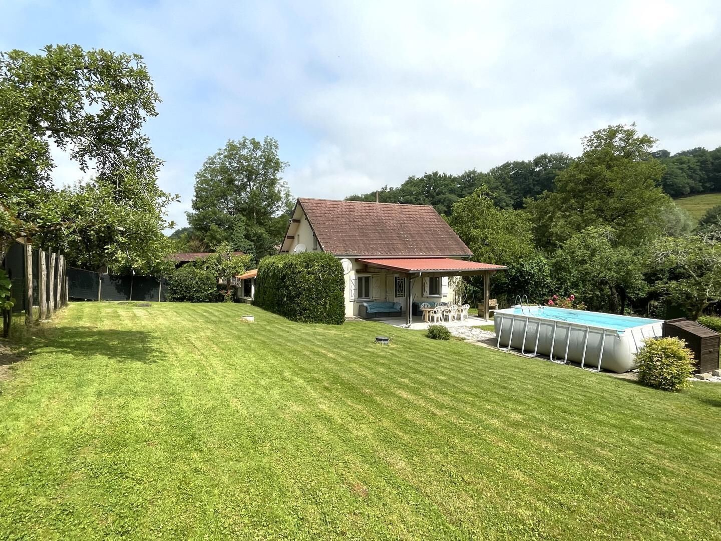 A house with a red roof, a swimming pool, and a well-maintained lawn.