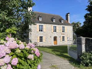 Un bâtiment en pierre avec une entrée centrale, de nombreuses fenêtres et un petit porche.