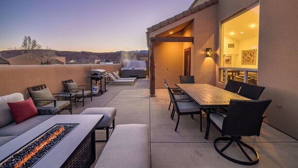 Une terrasse extérieure avec une table à manger, des chaises et un foyer.