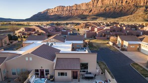 Un quartier résidentiel avec des maisons modernes, une terrasse dotée de mobilier d’extérieur et une montagne en arrière-plan.