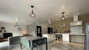 A modern kitchen with a dining area, a TV, and a stone wall. - BARRANDEIA - JUXUE - Gîte (JUXUE)