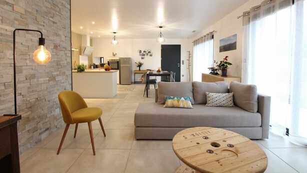 A modern living room with a sofa, a yellow chair, a wooden coffee table, and a stone wall. - BARRANDEIA - JUXUE - Gîte (JUXUE)