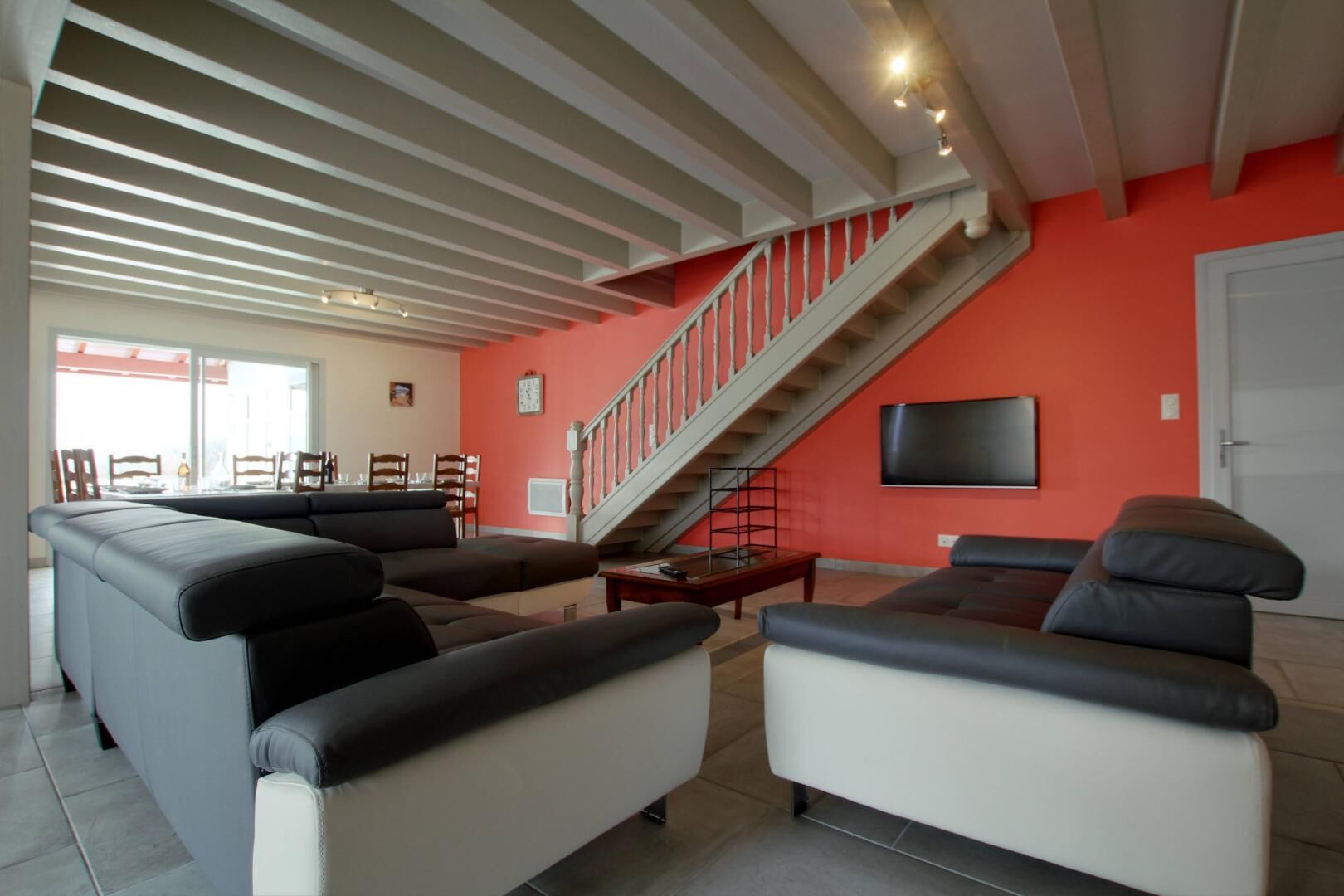 Ein geräumiges Wohnzimmer mit einer großen Couch-Gruppe, einer Treppe und einem flachbildfernseher an der Wand.