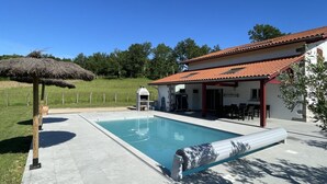 A swimming pool with a pergola and a barbecue area, surrounded by a house with a tiled roof. - BORDAZARRIA - JUXUE - Gîte (JUXUE)