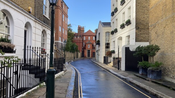 A narrow street lined with traditional buildings, featuring a black metal fence, a street lamp, and a clear blue sky. - Wonderful Chelsea Flat, 2 Bedrooms, 2 Bathrooms (London)