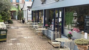 An outdoor café with tables and chairs, a brick pathway, and a sign that reads "Happy Hour". - Wonderful Chelsea Flat, 2 Bedrooms, 2 Bathrooms (London)