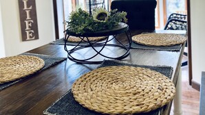 Una mesa de comedor con individuales tejidos, un centro de mesa con flores y un letrero que dice "LAKE LIFE".