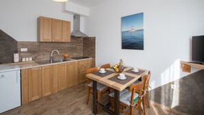 A modern kitchen with wooden cabinets, a built-in stove, and a dining area with a table and chairs. - New apartment Marin Punta-Umag near the sea (Umag)